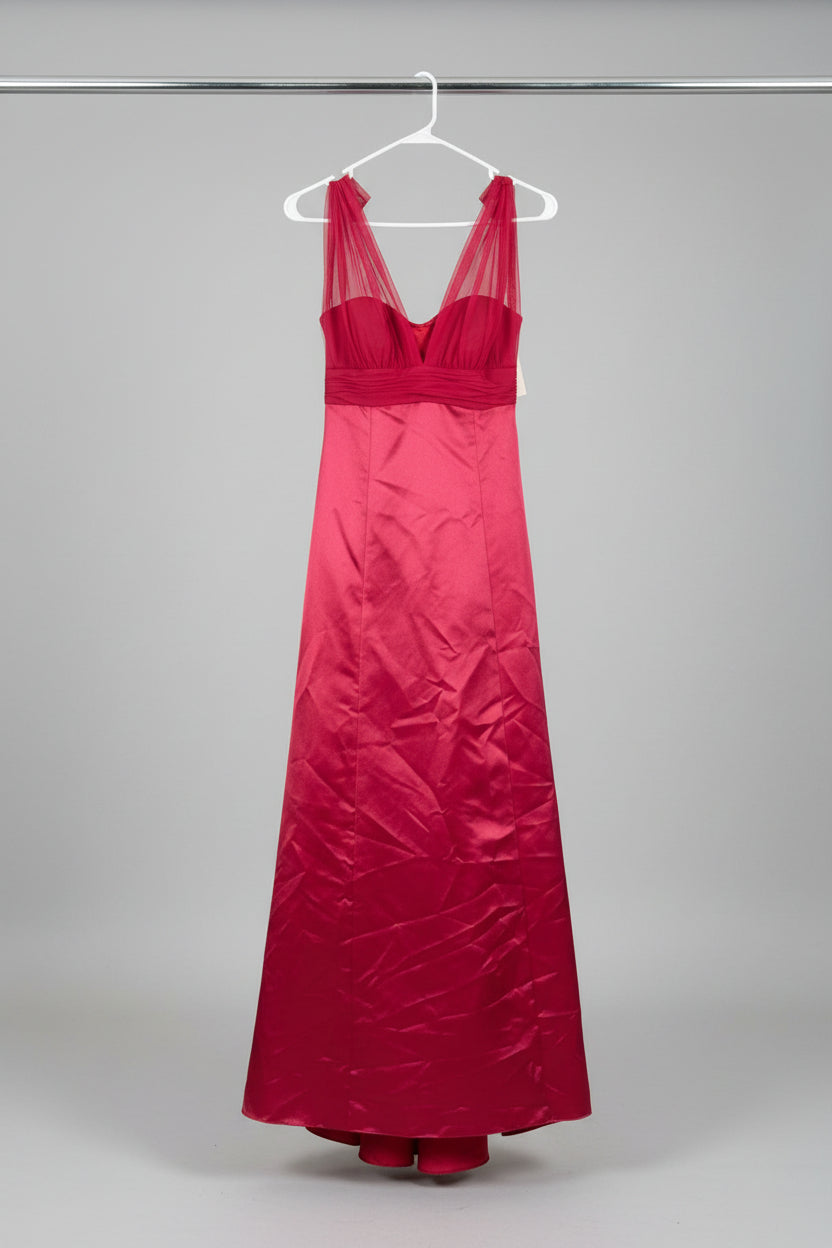 A bright red sleeveless maxi dress hanging on a clothes rack outdoors on a grassy lawn, with another dress partially visible on the left.