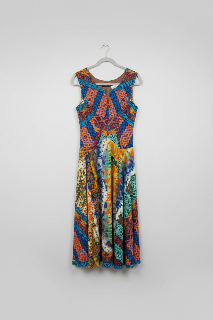 A colorful sleeveless dress with a vibrant geometric and tribal-inspired print in blue, orange, yellow, and green, hanging on a hanger in a retail store setting. 