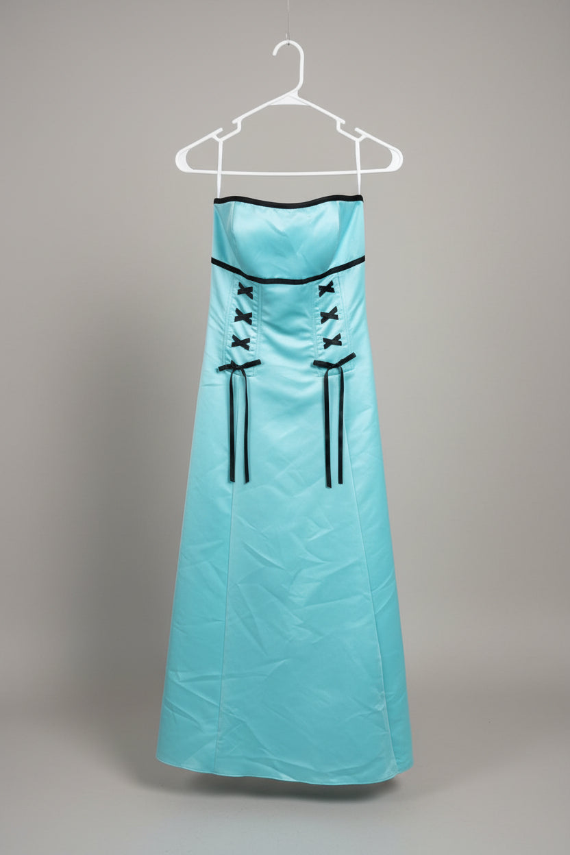 Two strapless formal dresses hanging on white hangers outdoors on a metal rack. The dress on the left is coral pink, and the dress on the right is light aqua blue with black trim and lace-up details.
