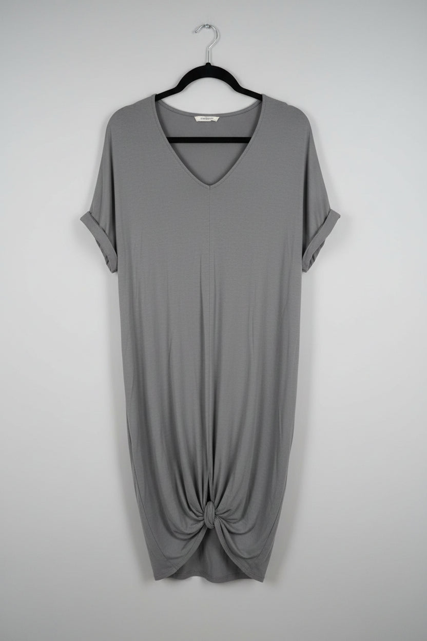 A gray short-sleeve V-neck top hanging on a black hanger in front of a white door.