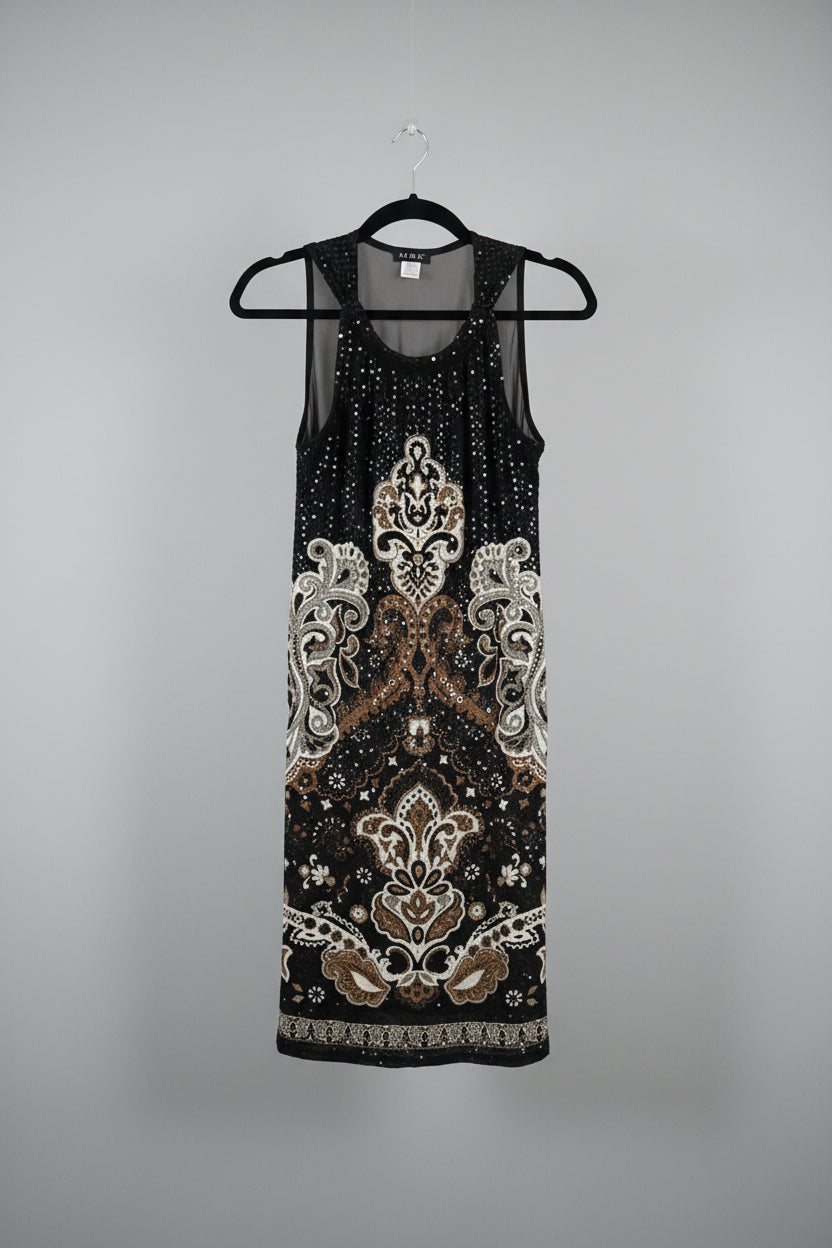 A sleeveless black dress with a white and brown ornate pattern, hanging on a black hanger in front of a white door.